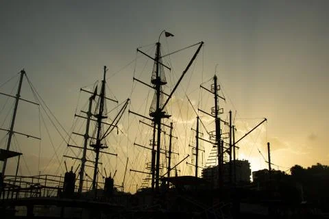 Silhouettes of ship masts on the sunset sky background. Photos