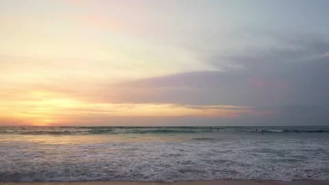 Silhouettes of surfers surfing at beach on sunset in summer orange sky Stock Footage 132677458