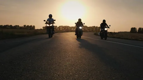 Silhouettes of three motorcyclists passing by the camera Stock Footage 192371866