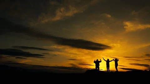 Silhouettes of three tourists against the backdrop of a sunset. Stock Footage 312192062