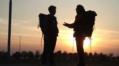 Silhouettes of two backpackers / having fun and trying to stop some car Stock Footage 51312659