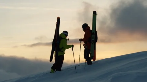 Silhouettes of two freeride skiers watching sunrise in Swiss Alps Video stock 129086366