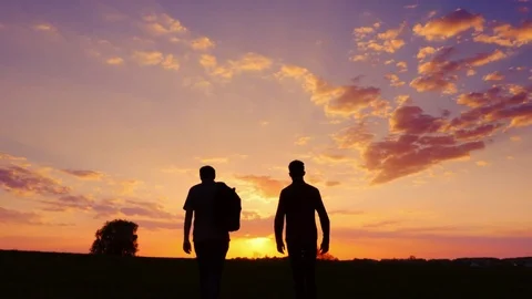 Silhouettes of two men - son and father go together to meet the sunset. Back Stock Footage 75150794