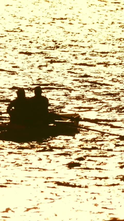 Silhouettes of two people paddling while sitting in a boat on the river at Stock Footage 328290375