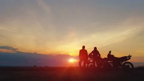 Silhouettes two riders with their bikes on the background of beautiful sunset.  Stock Footage 108727643