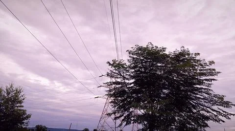 Silhouettes Under Cloudy Sky with Power Lines 写真素材