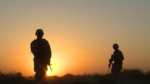 Silhouettes of US soldiers walking through the steppes of Afghanistan at sunset Stock Footage