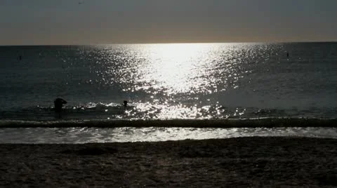 Silhouettes walking on the beach before sunset Stock Footage 21783629
