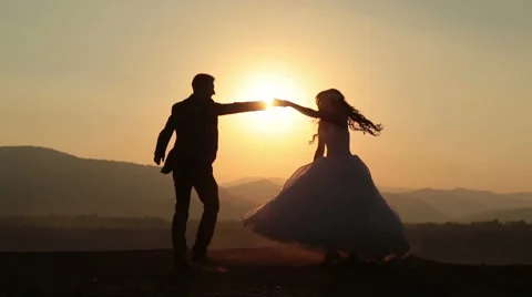 Silhouettes of wedding couple gracefully dances in the mountains Stock Footage