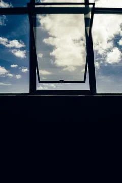 Silhouettes of a window structure looking towards the clouds in a blue sky Stock Photos