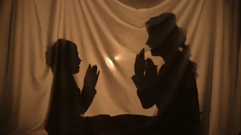 Silhouettes of woman and boy telling stories using shadow play, clapping their Stock Footage