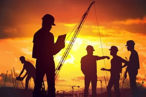 Silhouettes of workers working on construction site at suset. Stock Photos