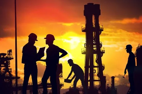 Silhouettes of workers working on construction site at suset. Stock Photos