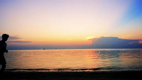 Silhouettes of young men are running on tropical beach at amazing sunset. slow Stock Footage 101067153