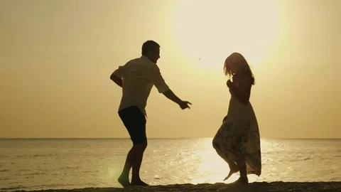 Silhouettes of young people dancing happily on the beach Stock Footage 80078609