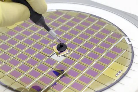 Silicon wafer with microchips, fixed in a holder with a steel frame on a gray Stock Photos