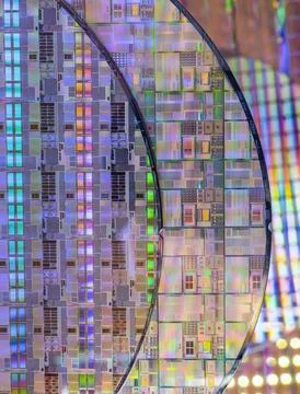 Silicon wafer with microchips reflecting different colors. Stock Photos