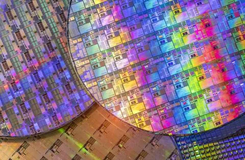 Silicon wafer with microchips reflecting different colors. Stock Photos