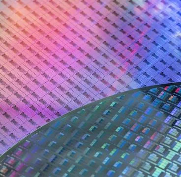 Silicon wafer with microchips reflecting different colors. Stock Photos