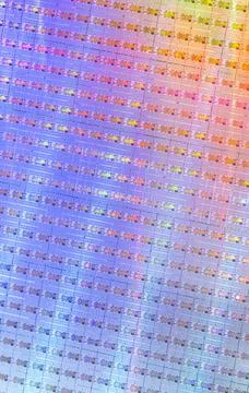 Silicon wafer with microchips reflecting different colors. Stock Photos