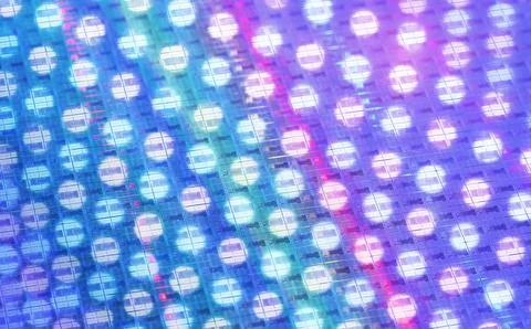 Silicon wafer with microchips reflecting different colors. Stock Photos