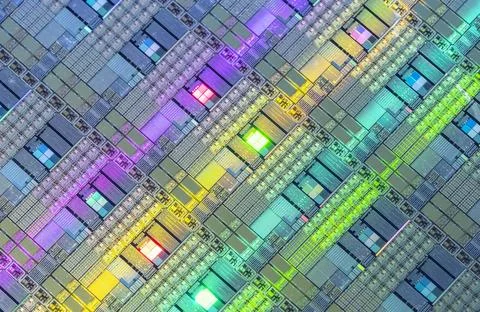 Silicon wafer with microchips reflecting different colors. Stock Photos