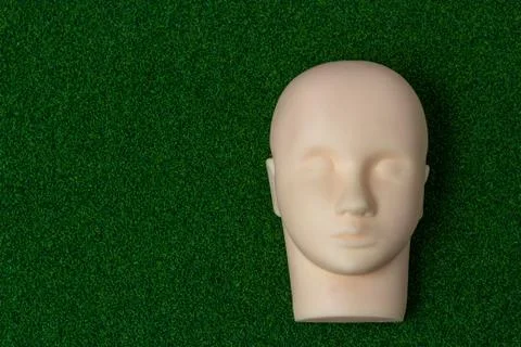 A silicone mannequin for basic training eyelash extension on green background Photos