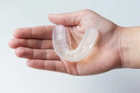 Silicone mouth guard for bite alignment or teeth whitening on human palm Stock Photos