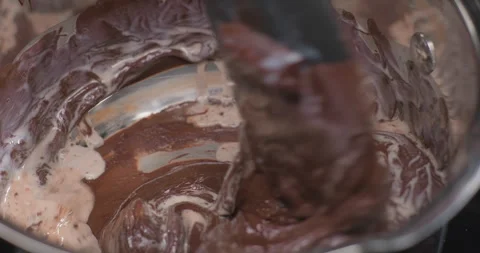 Silicone spatula stirs dark melted chocolate with cream or milk in a pan Stock Footage 253641812