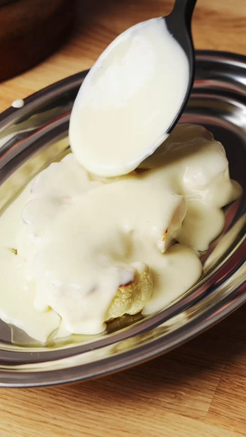 Silicone spoon pours white sauce over cauliflower. Stock Footage 342105434