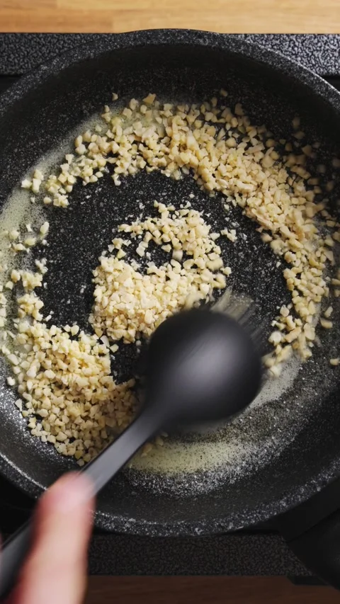 Silicone spoon stirs chopped almonds, cooking them in melted butter. Stock Footage 341950758