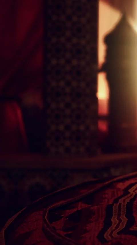 Silk curtains flutter in a candlelit room with patterned walls and rich fabrics Video stock 335190250