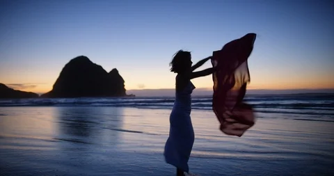 Silk dancer waves a red scarf by the ocean at sunset, Piha Stock-Footage 125416389