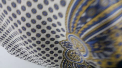 Silk fabric with elegant oriental patterns falls onto a flat white background.  Vídeo Stock 337402480