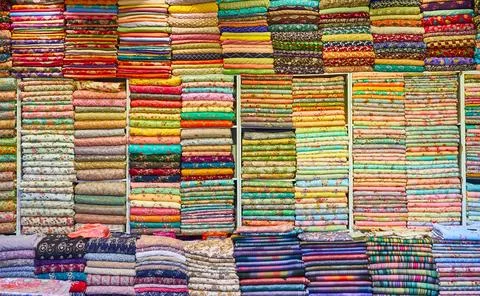 Silk multi-colored fabrics lie on the shelves of the store Stock Photos