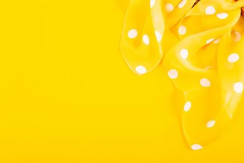 Silk patch of white polka dot fabric on a yellow background. The concept of.. Fotos de archivo