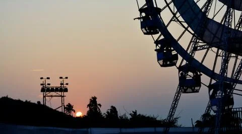 Sillhouetes of ferris wheel and trees during sunset Stock Photos