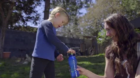 Silly child splatters bubble liquid around the yard Stock Footage 74118178