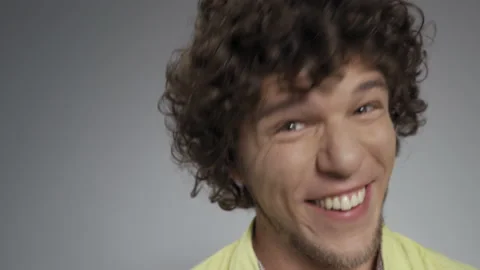 Silly face close up young guy with long curly hair isolated against a white Stock Footage 143617824