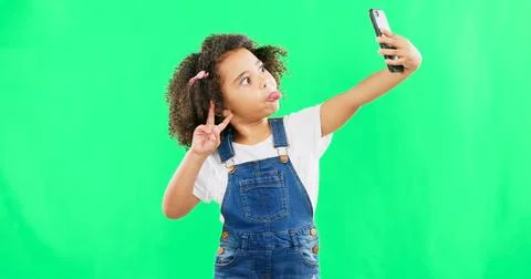 Silly little girl, selfie and peace sign on green screen with goofy facial Stock Photos