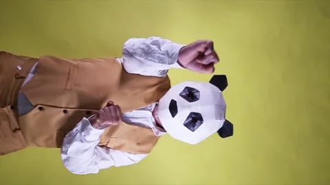 Silly man dancing and celebrating with a panda head mask on a yellow backgrou Stock Footage 211987045