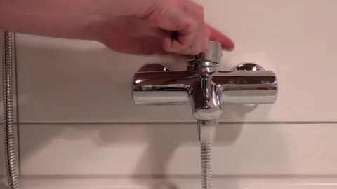 Silly man playing with water tap, tapping on the tap, faucet drumming, on, off Stock Footage 76804695