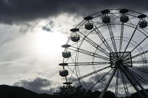 Silohuette Ferris wheel in backlight on cloudy sky Stockfoto's
