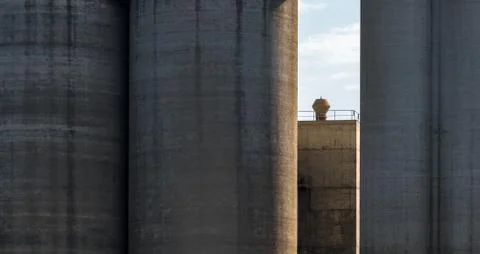 Silos made of solid concrete and a chimney standing in the sunshine Stock Photos