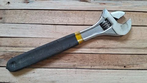 Silver adjustable wrench with a black handle on wooden planks Stock Photos