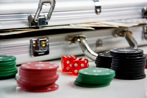 A silver aluminum case with poker chips, dice, and cash inside, sitting on .. Stock Photos
