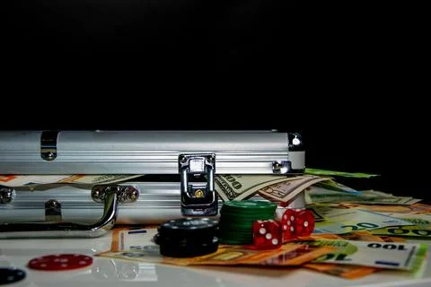 A silver aluminum case sits on a table with stacks of cash and poker chips Stock Photos