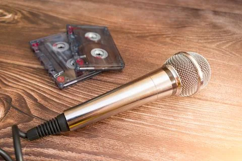 A silver analog microphone sits next to old cassette tapes Stock Photos