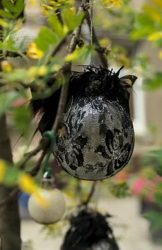 Silver and black patterned Christmas ornament on a green tree branch in summer. Stock Photos