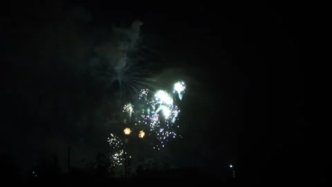 Silver and light blue sparks scatter fireworks on the black night sky above.. Video stock 293363231